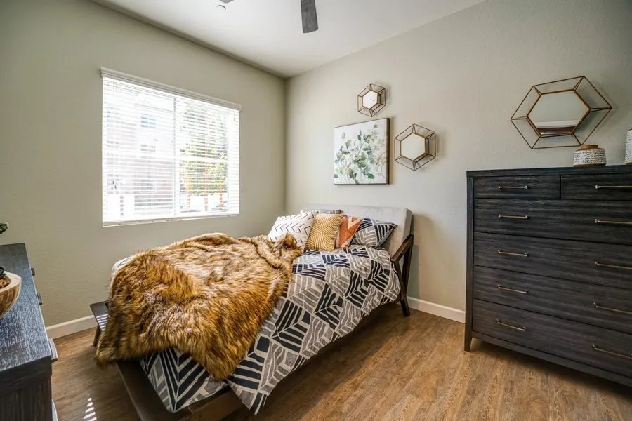 Apartment bedroom with a patterned bed and a dark wood dresser