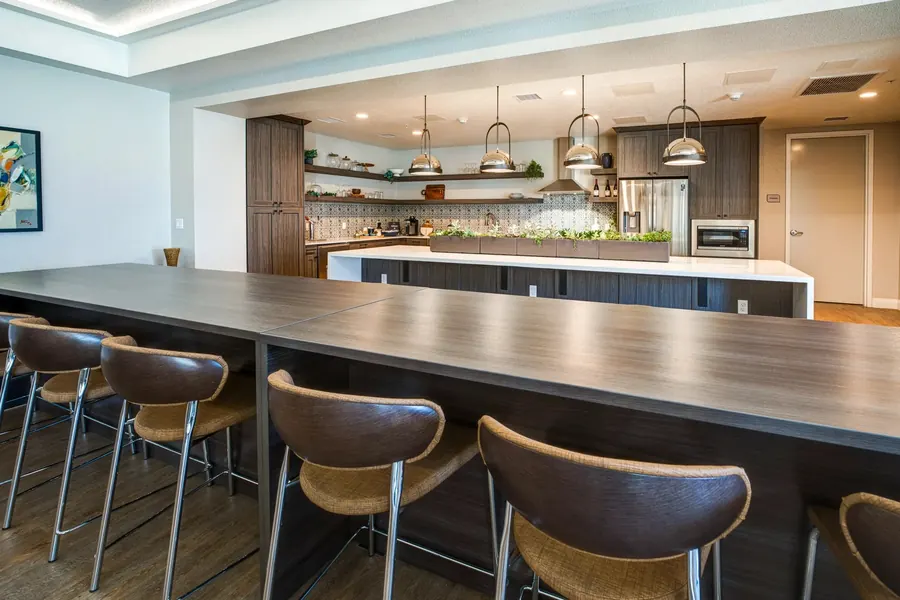 Apartment clubhouse kitchen with a long counter, bar stools and pendant lights