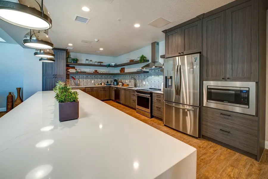 White kitchen island and stainless steel appliances in a clubhouse kitchen