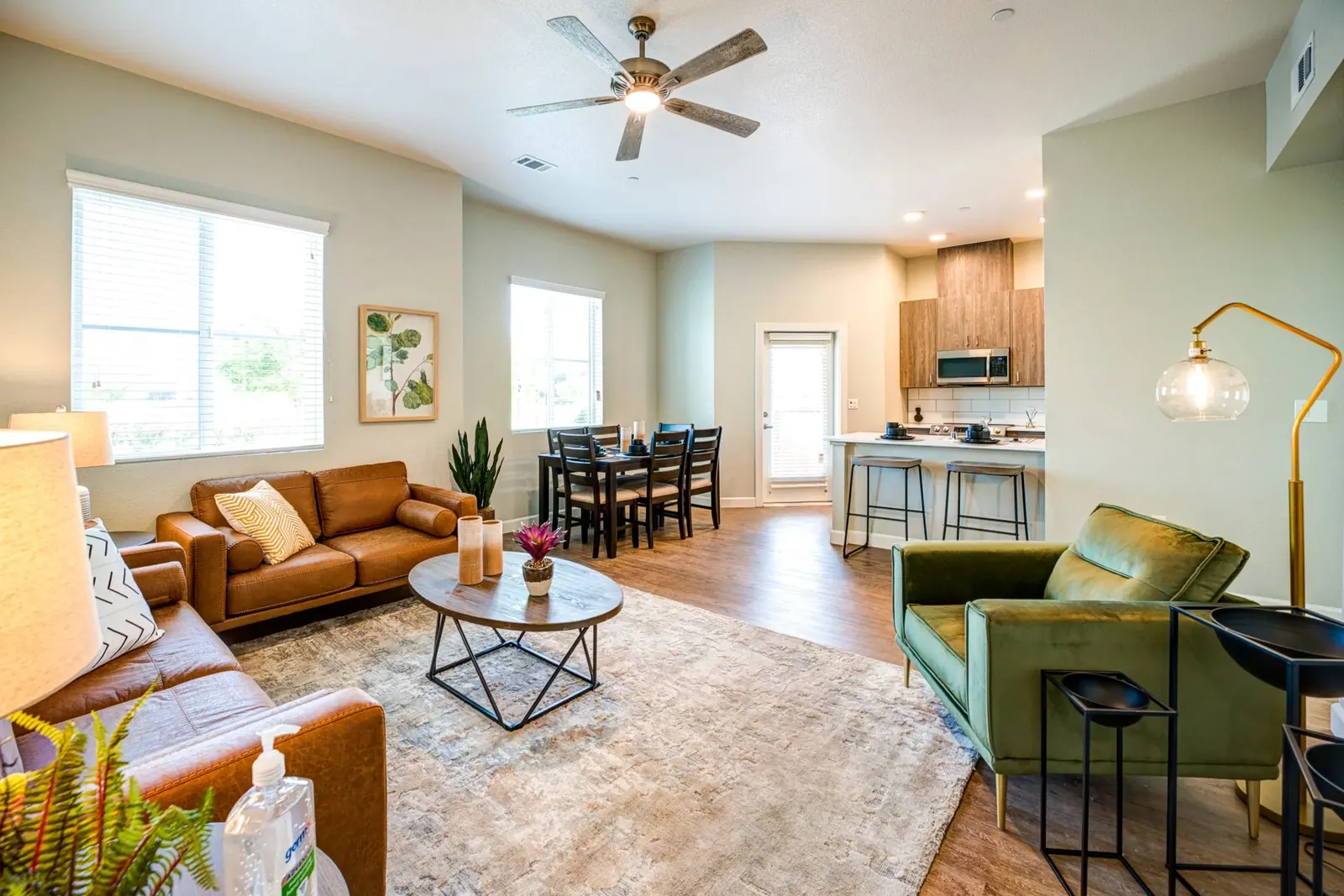Furnished apartment living room with a leather sofa, green armchair and a dining table beyond