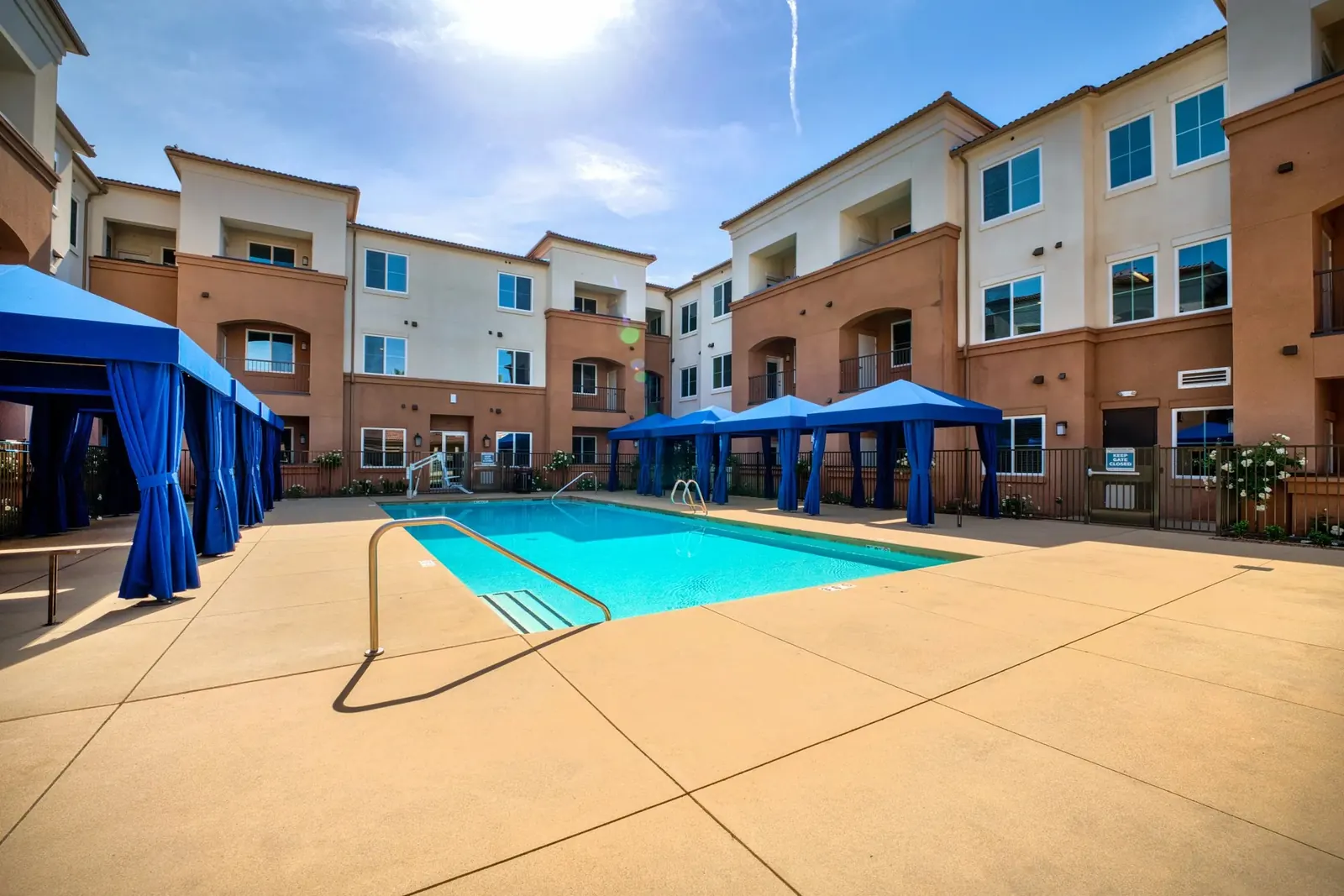 Apartment community pool with shaded cabanas and a three-story courtyard building