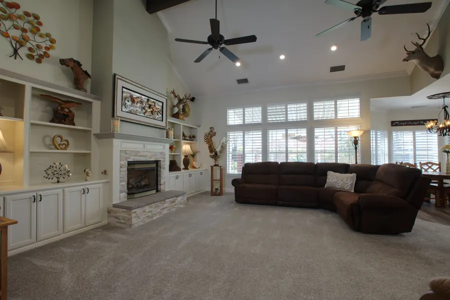 Home living room with a fireplace, built-in shelves and tall windows
