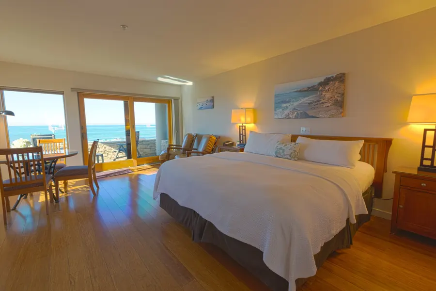 Hotel suite with a king bed, wood floors and ocean-facing windows